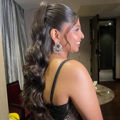 A glamorous high ponytail with beautiful, structured waves. This is a statement hairstyle, perfect for a reception or cocktail event, especially when paired with a modern lehenga.