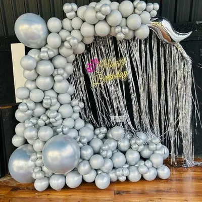 An example of our birthday party decorations. This stylish setup includes a silver tinsel backdrop framed by a large organic balloon arch in metallic silver, perfect for creating a glamorous photo booth at any celebration.