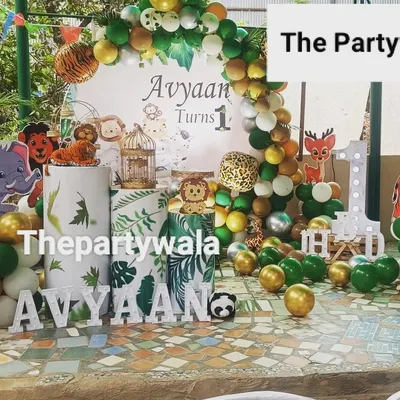 An amazing outdoor jungle safari party! The decorations look fantastic in a garden setting. The setup includes a custom backdrop, animal cutouts, and themed pedestals.