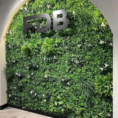 An elegant artificial vertical garden installed in an arched alcove for an office reception area, complete with company branding.