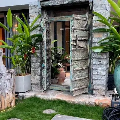 A closer look at the antique door feature. The weathered texture of the wood and stone creates a stunning contrast with the fresh green lawn, making it a true statement piece.