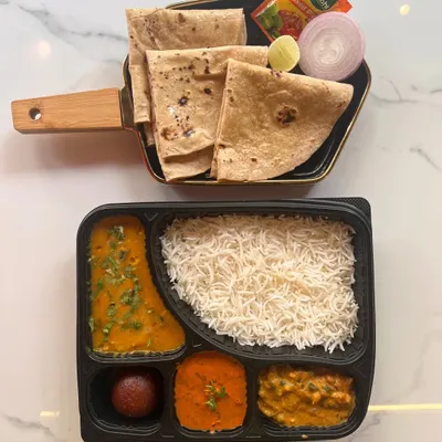 A classic North Indian vegetarian thali, neatly packed and ready to serve. This meal box includes two vegetable curries, dal, steamed rice, rotis, and a gulab jamun, offering a complete and traditional dining experience for your event.