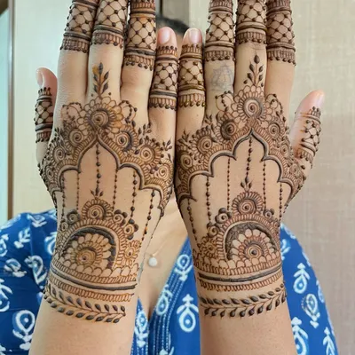 A beautiful semi bridal mehndi design for a wedding guest, featuring matching intricate patterns on both hands. The design includes detailed archways, hanging elements, and leafy wrist cuffs.