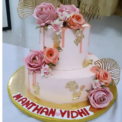 A stunning two-tiered engagement cake in soft pink, adorned with fresh roses, gold leaf, and a drip effect. I love creating these romantic centerpieces.