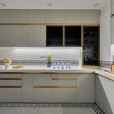 This kitchen is a masterclass in modern elegance. Sleek grey cabinets with gold handles, a patterned tile border, and under-cabinet lighting create a look that is both sophisticated and highly functional.