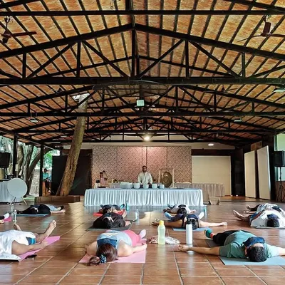 A large group experiences deep rest during a sound meditation workshop in a beautiful, open-air hall. This setting allows participants to connect with both the healing sounds and the tranquility of nature.