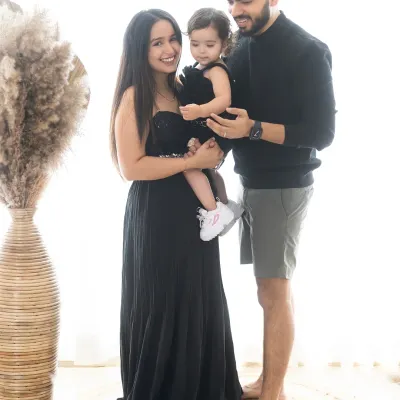 A lovely candid family portrait. The parents are sharing a smile while holding their little girl, a simple, happy moment captured forever.