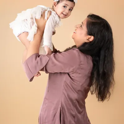 A mother's joy as she lifts her baby girl high. These are the playful, candid moments that make the best memories.