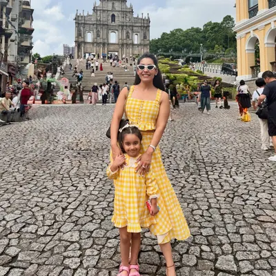 Creating memories on vacation is even more special in matching outfits. I designed this bright yellow gingham check co-ord set, featuring a crop top and asymmetrical skirt for myself, and a matching dress for my little one. It’s the perfect custom vacation look for a mother-daughter duo.