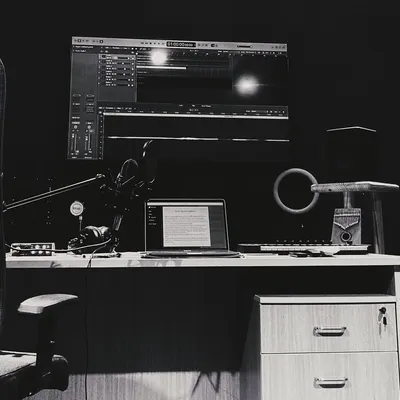 A black and white photo of my home studio setup. This is where the magic happens, from doodling lyrics on my laptop to recording the final vocals.