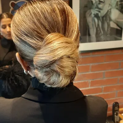 A perfect example of a classic, sleek low bun. This timeless hairstyle is versatile and elegant, suitable for brides, family members, or guests at any formal event.