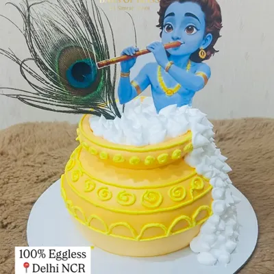A divine centerpiece for your Janmashtami celebration. This cake features a beautiful figurine of Lord Krishna playing his flute, emerging from a pot of butter, and is adorned with a real peacock feather.