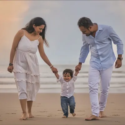 Hand in hand, taking their first steps as a family on the wet sand. This image captures the story of guidance and love as parents lead their little one on a seaside adventure.