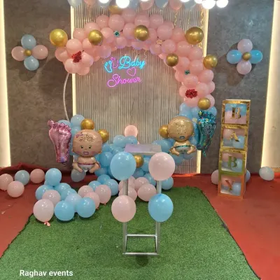 A complete baby shower setup with a pink and blue balloon arch, a "Baby Shower" neon sign, and cute baby foil balloons. The artificial grass carpet adds a nice touch to the decor.