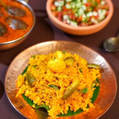 A close-up of Tondli Bhaat, a classic Maharashtrian rice dish, served on a banana leaf atop a copper plate. The styling highlights the simple, wholesome ingredients that define home-style Marathi cooking.