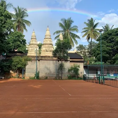 A stunning view of our court with a rainbow overhead, right next to the serene temple. This truly captures the "divine tennis experience" we aim to provide.