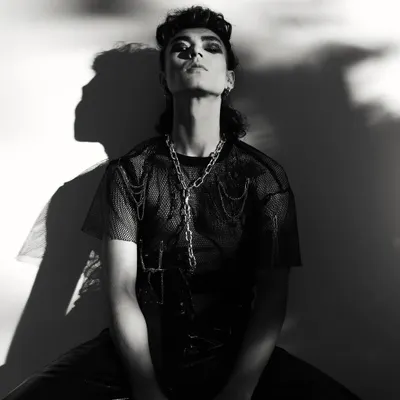 A dramatic, high-contrast black and white portrait from a punk-inspired men's editorial. The play of harsh light and deep shadow creates a powerful, graphic image.