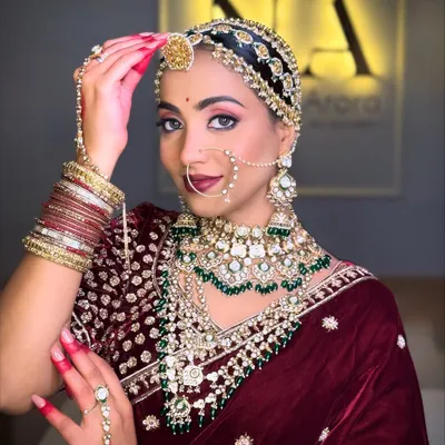 A royal Marwadi bride in a deep velvet lehenga. The look features dramatic eyes, bold red nails, and intricate jewelry, including a traditional sheeshpatti, to create a timeless and elegant style.
