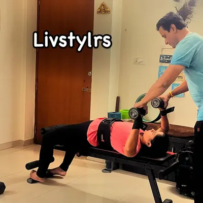 I am spotting a client during a dumbbell chest press. This ensures she can push her limits safely while maintaining correct form for chest and shoulder strength.