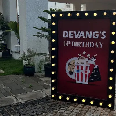 A movie-themed birthday party entrance sign with marquee lights, perfect for a unique celebration at home.