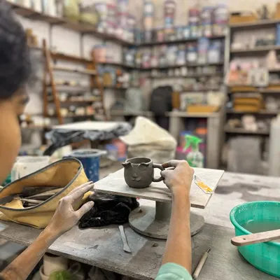 Create a piece that is entirely your own. This image captures a participant in our 'Make Your Own Cup' workshop, focused on sculpting a handle for their creation in our fully equipped studio.