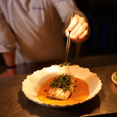 Our chef meticulously adds the final garnish to a dish. This attention to detail is at the heart of our culinary philosophy.
