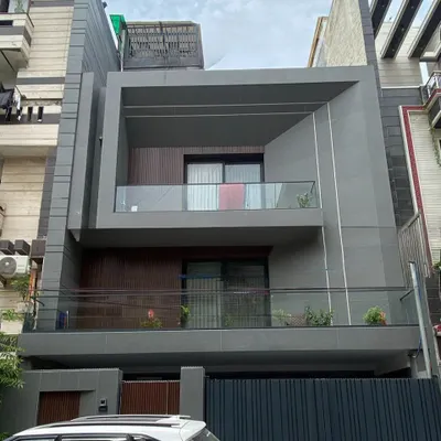 The completed facade of the Delhi residence, shown as a 3D render in image 18. This real-world photo confirms the faithful execution of the design's core elements, from the recessed wooden paneling to the prominent grey frame of the upper balcony.
