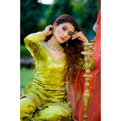 A vibrant outdoor portrait of a model in a lime green velvet suit, accessorized with a statement necklace. The natural lighting beautifully captures the fabric's sheen and the jewelry's detail for a fashion campaign.