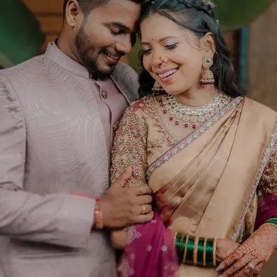 A candid moment of shared laughter between Karishma and Bhaskar, showcasing the beautiful embroidery on the bride's blouse and her traditional green bangles.