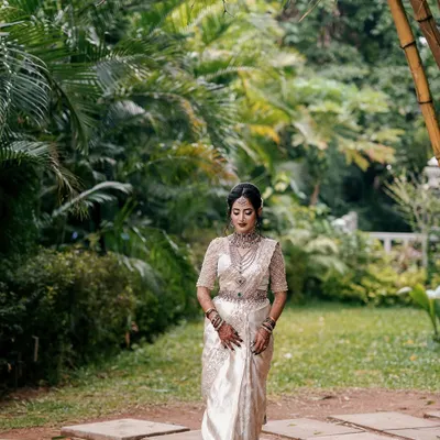 A full-length shot of the beautiful Dr. Ankita, showcasing how the intricate mehendi on her hands and feet complements her stunning white and silver saree and traditional jewelry.