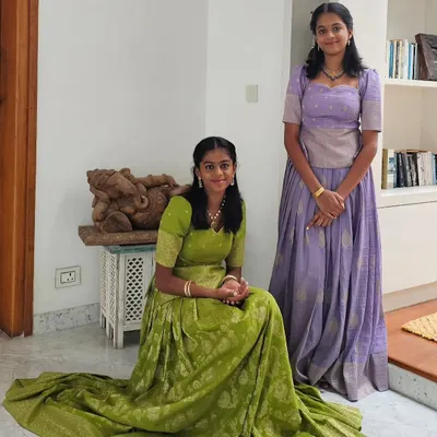 Custom-designed traditional lehengas for two sisters. The lime green and soft lavender brocade outfits feature intricate patterns and are tailored for a perfect fit, allowing each sister to have her own distinct yet coordinated style for the special event.