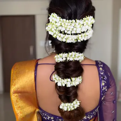 A detailed shot of a traditional South Indian bridal braid, beautifully adorned with fragrant jasmine flowers (gajra). This classic hairstyle is the perfect finishing touch for a traditional look.