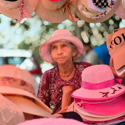A candid portrait of an elderly woman selling hats at a market in Goa. Her expressive face tells a story of a life lived by the sea, captured using my OPPO phone's portrait mode.