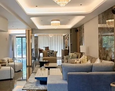 This expansive living area in a neoclassic villa embodies our approach to timeless elegance. We designed the space with multiple seating zones, coffered ceilings with bespoke chandeliers, and a seamless flow to the outdoors, creating an environment of sophisticated comfort.