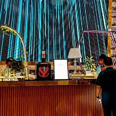 A sleek, modern bar with a wooden finish set against a massive digital LED screen, creating a dynamic and high-tech backdrop for a wedding cocktail event.
