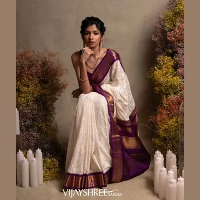 A masterpiece of fusion, this white Kanjivaram saree is adorned with exquisite Chikankari hand embroidery, set against a rich purple border and pallu.
