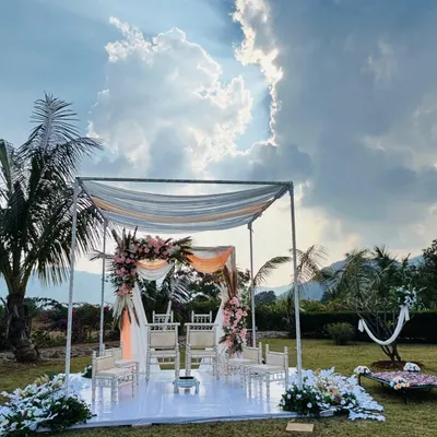 A breathtaking view of the minimal mandap set against a dramatic sky in Lonavala. The simple structure with light draping allows the natural landscape to be a part of the decor.