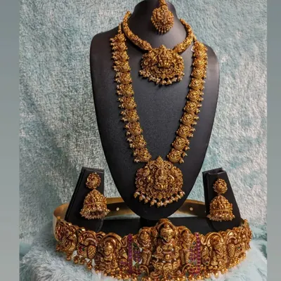 This is the quintessential full bridal temple jewellery set for a traditional South Indian wedding. It includes a choker, a long Laxmi haaram, matching jhumkas, and an intricate hip belt (vaddanam), all in a beautiful antique gold finish.