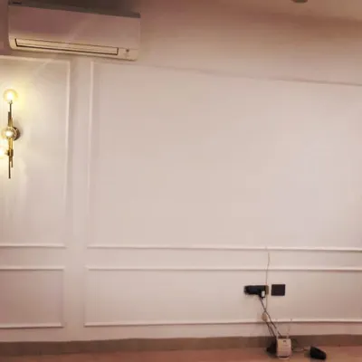 This is a project in progress, showing how we use simple moulding to create elegant, classic paneling on a living room wall. The design includes dedicated spaces for modern wall sconces, adding a layer of sophistication before the final touches.