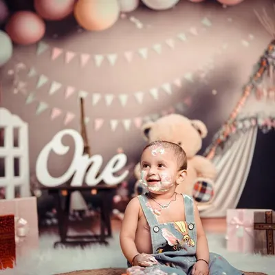 A first birthday cake smash is a memory you will treasure forever. This little one is having the time of his life, covered in cake and happiness in a setup filled with balloons and teddy bears.
