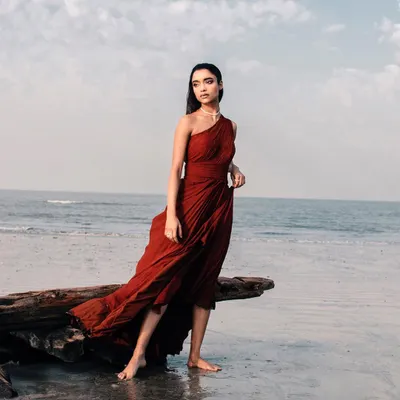 This stunning one-shoulder gown in a deep rust red is perfect for making an entrance. The lightweight, flowing fabric drapes beautifully and catches the sea breeze, making it an ideal rental choice for a pre-wedding photoshoot, a beachside cocktail party, or any elegant evening event.