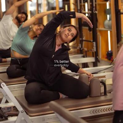 Progress isn't about giant leaps; it's about getting just 1% better every day. Here, a client focuses on a deep side stretch on the reformer, improving flexibility and control.