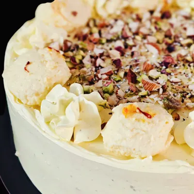 A close-up of my bestselling Rasmalai Cake, showing the rich texture from the homemade rasmalai, chopped nuts, and delicate saffron strands.