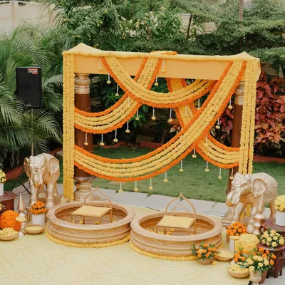 A traditional Haldi setup with a vibrant marigold backdrop. We used classic elements like urlis, brass bells, and elephant statues to create an auspicious and joyful setting for Ketaki and Rakesh's Haldi ceremony.