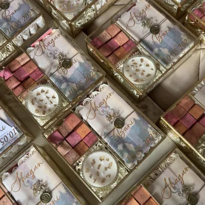 A stunning array of my glass box wedding invitation hampers. Each one is personalized with the couple's names and wedding date, containing gourmet sweets and a custom invitation card.