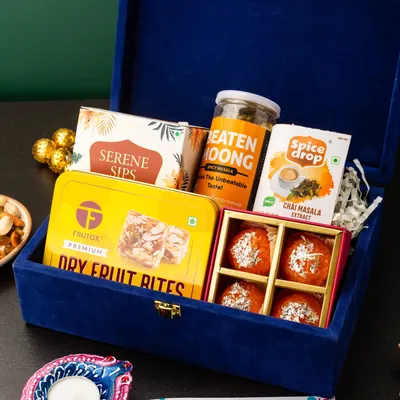 This luxurious royal blue velvet box is curated for a premium gifting experience. It contains a mix of healthy snacks like dry fruit bites and beaten moong, gourmet tea, and traditional motichoor ladoos, making it a perfect blend of health and indulgence for Diwali.