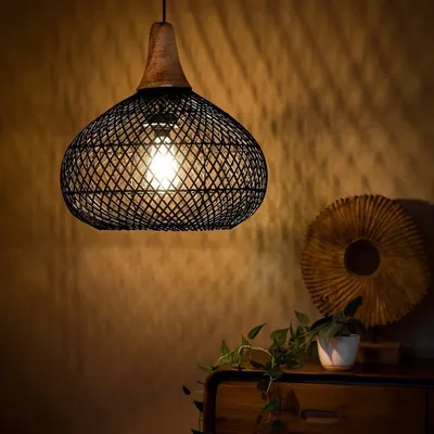 This black-dyed bamboo pendant, shown here in a cozy corner, demonstrates how a modern design can still create a warm, inviting atmosphere. The wooden top adds a touch of natural contrast, while the open weave casts beautiful, intricate shadows on the wall.