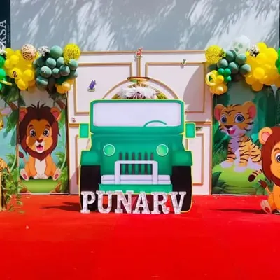 A full view of a jungle-themed birthday party setup. I used a large jeep cutout as the centerpiece, surrounded by cute animal characters, balloon garlands, and a personalized name sign for Punarv.