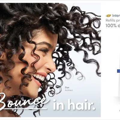 A dynamic advertisement for Dove's 'Intense Repair' range. The shot captures the joyful bounce of a model's curly hair, visually representing the campaign tagline "Fill Bounce in hair" alongside the product packshot.