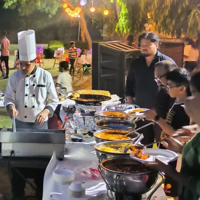 A guest favorite: our live cooking station. Here, a chef prepares a custom dish for a guest at an outdoor evening party, offering a personalized and engaging food experience.